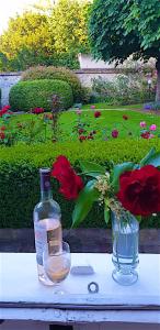 una botella de vino y un jarrón de flores sobre una mesa en CHAMBRES D'HÖTES DANS MAISON DE MAÏTRE DU XVIIIe SIECLE, en Houdan