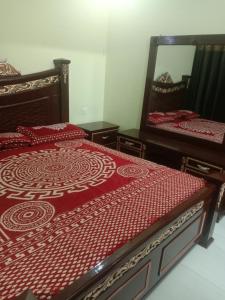 a bedroom with two beds and a mirror at Gujrat Guest House in Gujrāt