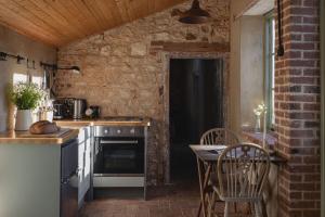 a kitchen with a stove and a table with chairs at The Little Potting Shed in Sedgeford