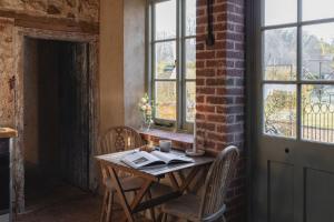 a table and chairs in a room with windows at The Little Potting Shed in Sedgeford