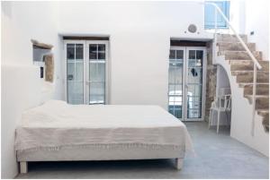 a white bedroom with a bed and a staircase at La Galerie - Art House Parikia in Parikia