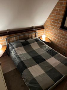 Ce lit se trouve dans une chambre dotée d'un mur en briques. dans l'établissement Dennenrust A-frame huisje middenin het bos., à Lanaken