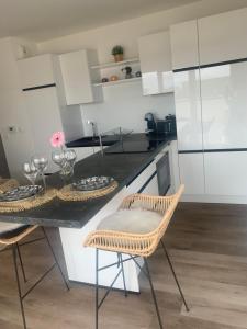 a kitchen with white cabinets and a table with chairs at Le Rooftop d’Isa in Colombelles