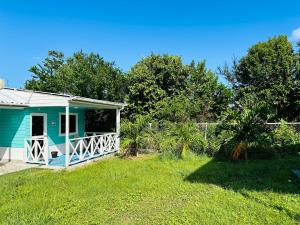 a small blue house in a grassy yard at Posada Camp Inn Providencia in Providencia