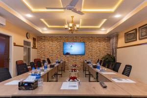 una sala de conferencias con mesas largas y una pantalla de proyección en The nexus Hotel Apartments, en Peshawar