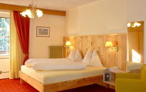 Habitación de hotel con cama con almohadas blancas en Carezza LAKE & RIVER Hotel, en Carezza al Lago