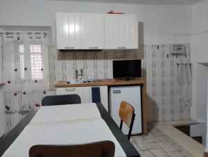 cocina con mesa, fregadero y armarios blancos en Casetta del borgo, en Montelaterone