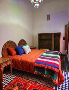 een slaapkamer met een bed met een oranje dekbed bij Dar Bryan in Fès