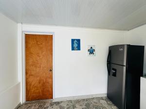 a kitchen with a refrigerator and a door in a room at Posada Camp Inn Providencia in Providencia