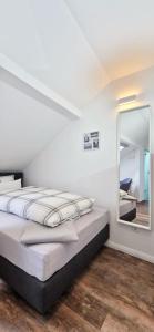 a white bedroom with a bed and a mirror at Gästehaus Teerlings Hafen in Borkum
