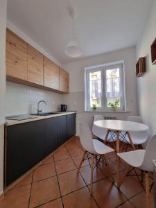 - une cuisine avec une table, des chaises et un évier dans l'établissement Apartament Korzenioskiego 7/2, à Przemyśl