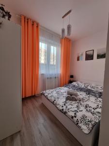 - une chambre avec un lit et un rideau orange dans l'établissement Apartament Korzenioskiego 7/2, à Przemyśl