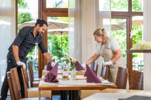 Ein Mann und eine Frau, die einen Tisch in einem Restaurant platzieren. in der Unterkunft Landhotel Annelie in Preußisch Oldendorf