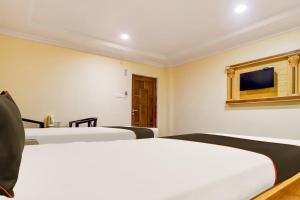 um quarto com duas camas e uma televisão na parede em Super Collection O Hotel Adithya Central em Elūru