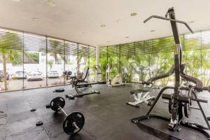 een fitnessruimte met cardio-apparatuur in een kamer met ramen bij Apartamento Cleo in Cancun