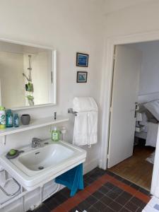 a white bathroom with a sink and a mirror at AQUARELLE in Avranches