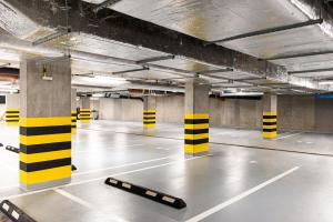 an empty parking lot with yellow and black poles in a parking garage at SHED Living Kraków in Kraków