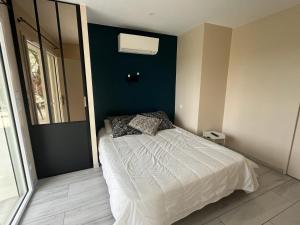 1 dormitorio con cama blanca y pared azul en Gîte du Pin avec Spa privatif, en Pey