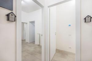 einen Flur mit weißen Wänden und einem Spiegel in der Unterkunft Mutina Design Suite - City life & Hesperia Hospital in Modena