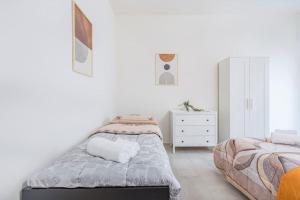 ein weißes Schlafzimmer mit 2 Betten und einer Kommode in der Unterkunft Mutina Design Suite - City life & Hesperia Hospital in Modena