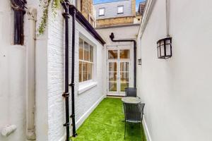 une allée vide avec une chaise et de l'herbe verte dans l'établissement Stunning 2BD flat in South Kensington with a patio, à Londres