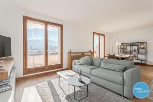 ein Wohnzimmer mit einem Sofa und einem Tisch in der Unterkunft L'Éclat D'annecy - Appartement Avec Vue Lac in Annecy