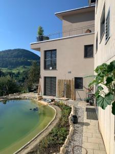 a house with a pond in front of it at Chez Svanette B&B Villa Sonnglück in Zullwil