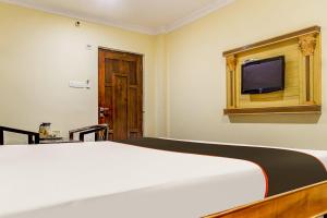 a bedroom with a bed and a tv on a wall at Super Collection O Hotel Adithya Central in Elūru