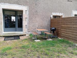 a picnic table and a grill in front of a building at Charmant Gîte Familial à Saint-Benoît-sur-Loire - 2 Chambres, Parking, Proche Patrimoine et Nature - FR-1-590-426 in Saint-Benoît-sur-Loire