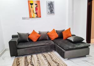 een zwarte bank met oranje kussens in de woonkamer bij Douglas Court Accra-Fantastic Living 1,2,3-Beds in Adenta, 5star Service, Free Wifi, 30mins to Airport, by DLA 