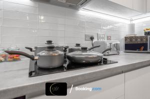 dos ollas sentadas sobre una estufa en una cocina en Stylish City Centre Escape, Serviced Accommodation in Birmingham Suitable For Families, Visitors & Contractors, Wi-Fi, Games & Netflix - By Noor Luxury Accommodations, en Birmingham