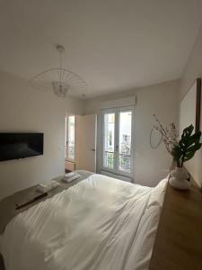 a bedroom with a large white bed with a vase of flowers at Cosy Apt 4P-porte maillot -palais des congrés in Paris