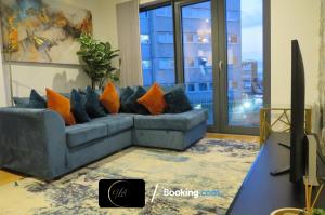 a living room with a blue couch with orange pillows at Stylish City Centre Escape, Serviced Accommodation in Birmingham Suitable For Families, Visitors & Contractors, Wi-Fi, Games & Netflix - By Noor Luxury Accommodations in Birmingham