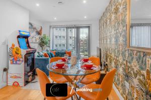a dining room with a glass table and orange chairs at Stylish City Centre Stay, Serviced Apartment in Birmingham Suitable For Families & Contractors, Wi-Fi & Netflix - By Noor Luxury Accommodations in Birmingham