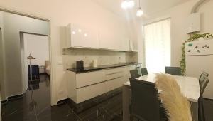 uma cozinha com armários brancos e uma mesa com cadeiras em Tra centro e mare - Intero appartamento con parcheggio em Savona