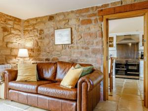 un sofá de cuero en una sala de estar con una pared de piedra. en 1 bed in Meerbrook 87507 en Meerbrook