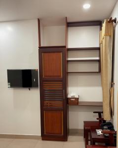 a room with wooden shelves and a tv on a wall at DINH DINH 2 AIRPORT HOTEL in Ho Chi Minh City