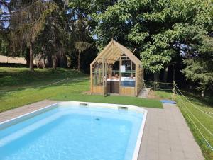 une petite serre à côté d'une piscine avec une maison dans l'établissement AGRITURISMO VALDISPINSO, à Santa Vittoria dʼAlba