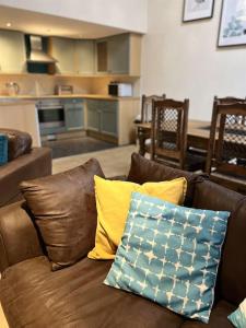 ein Wohnzimmer mit einer braunen Couch mit Kissen in der Unterkunft Grand Mill: Near to Shops, Attractions, Restaurant in Burton upon Trent