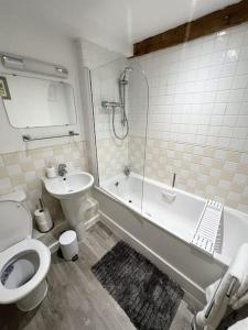 a bathroom with a toilet and a tub and a sink at Grand Mill: Near to Shops, Attractions, Restaurant in Burton upon Trent
