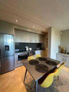 cocina con mesa y sillas amarillas en Luxury Vineyard Apartment, en Ciudad del Cabo