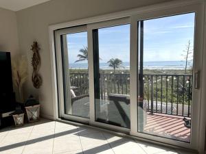 a room with sliding glass doors with a view of the ocean at Ocean Front in Cocoa Beach in Cocoa Beach