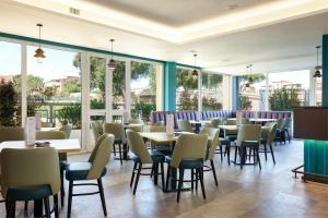 a restaurant with tables and chairs and windows at Hotel Roma Tor Vergata in Tor Vergata