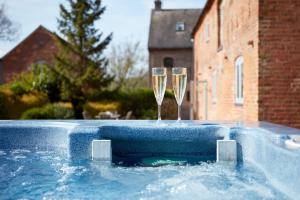 two champagne glasses sitting on top of a swimming pool at Finest Retreats - Nether Burrows Farm in Ashbourne