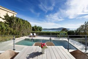 a patio with a wooden table and chairs and a swimming pool at Sunnydaze, 4 bed V/F pool villa in Villefranche-sur-Mer