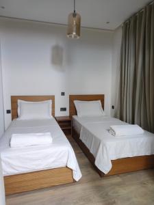 um quarto com 2 camas e lençóis brancos em Hivernage, Superbe appartement dans une résidence em Agadir