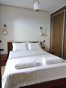 um quarto com uma cama branca e 2 almofadas em Hivernage, Superbe appartement dans une résidence em Agadir
