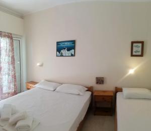 a white bedroom with two beds and a window at Ambrosia studios in Makry Gialos