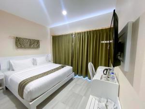 a bedroom with a bed and a television and a desk at Flamingo Ceria in Labuan Bajo