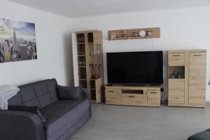 een woonkamer met een bank en een flatscreen-tv bij NEU! Ferienwohnung Nickel in Ahausen